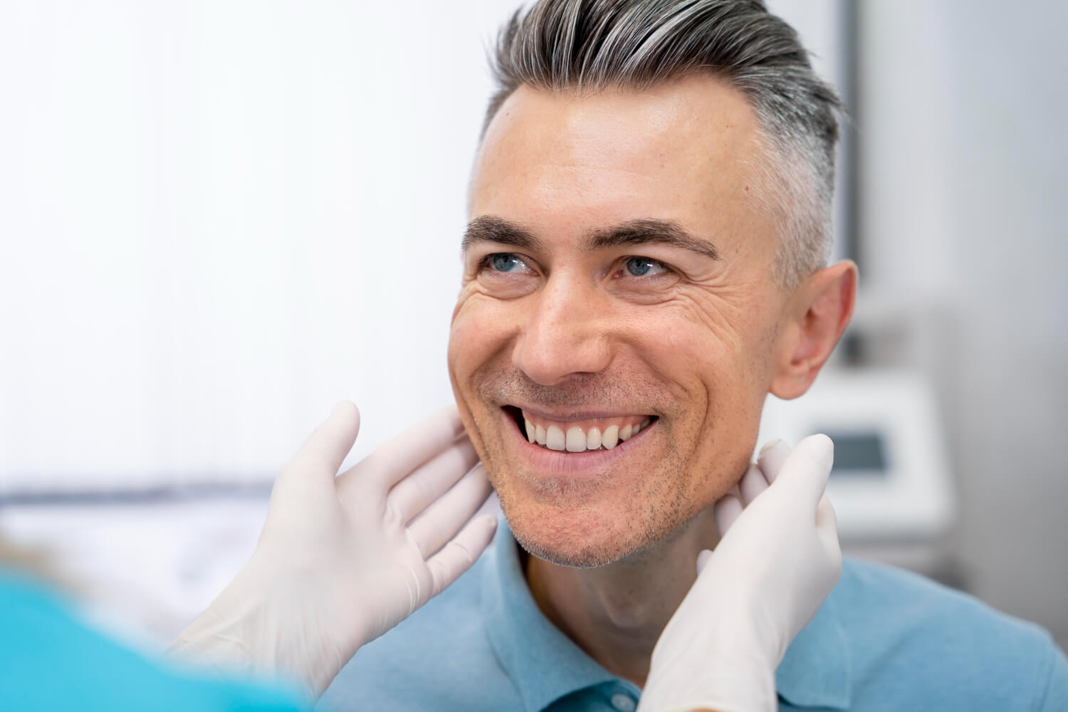 Homem de meia-idade sorrindo satisfeito enquanto dentista avalia resultado de protocolo de porcelana na Clínica Aoun em Guarulhos.