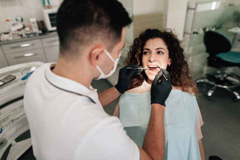 Dentista examina dente com canal tratado de paciente na Clínica Aoun em Guarulhos, prevenindo o escurecimento dental.
